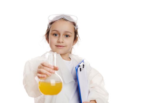 Charming smart schoolgirl in lab coat, holding out a laboratory flask with liquid chemical, isolated on white background