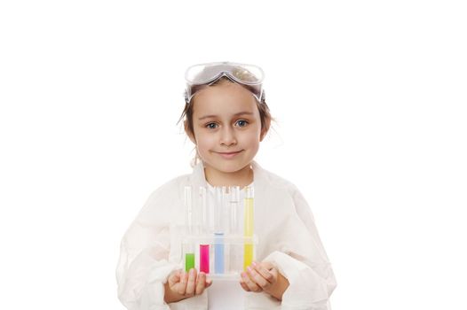 Caucasian smart child girl in lab coat, learns science chemistry, holds test tubes makes experiment at school laboratory