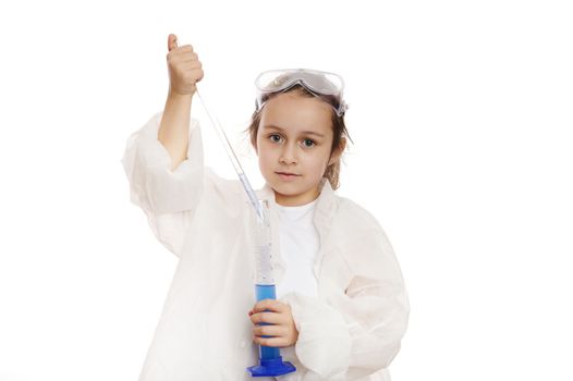 Smart preschooler little girl fills graduated pipette with liquid from measuring cylinder in practical chemistry class