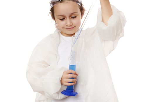 Close-up little girl fills the glass laboratory graduated pipette with a blue chemical solution from measuring cylinder