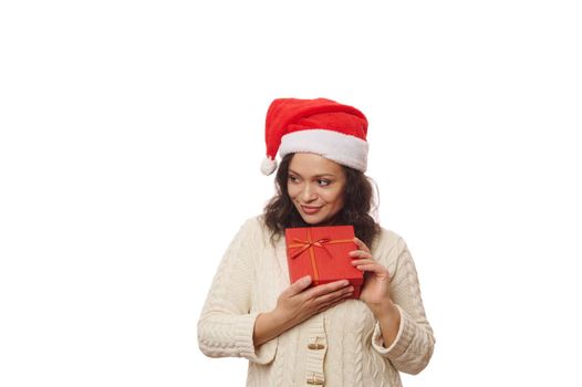 Beautiful woman in Santa hat with Christmas present over white background. Boxing Day. Time to open gift boxes. New Year