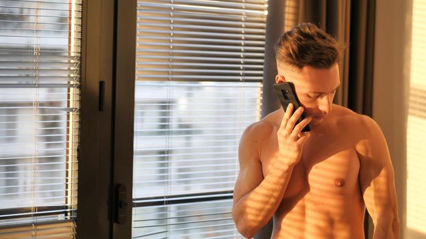 Attractive young man shirtless using cell phone