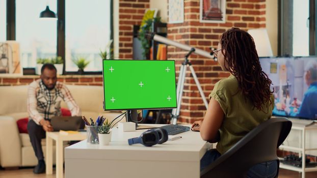 Female freelancer using computer with greenscreen
