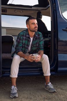 man sitting in the door of his camper van