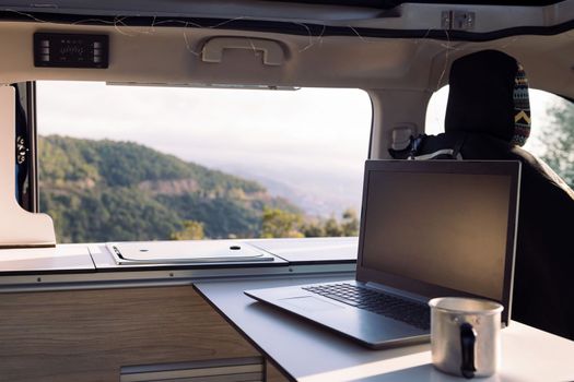 table of a camper van with a laptop and a mug