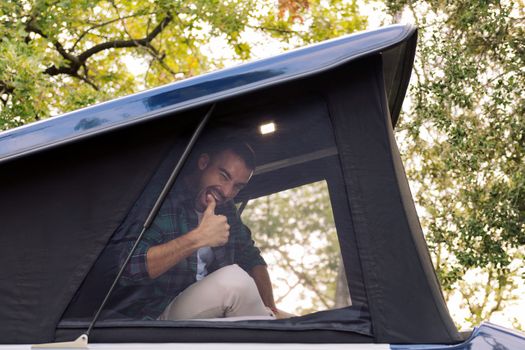 man giving a thumbs-up from the tent of his camper