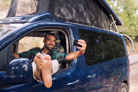 man taking a selfie sitting on his camper van
