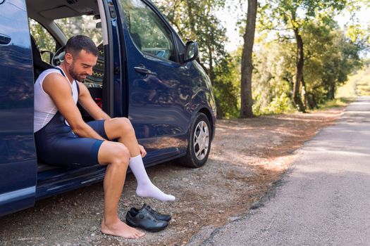 man dressing sitting on his van to go cycling