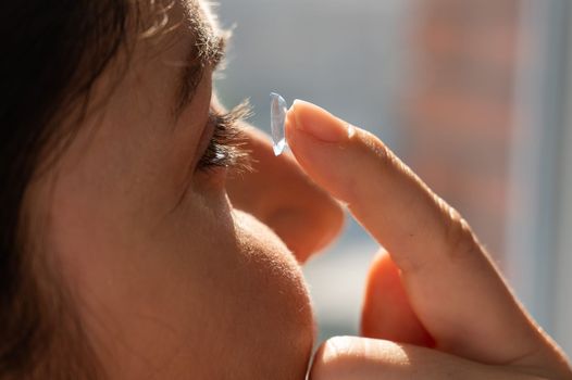 Close-up portrait caucasian woman putting on a contact lens.