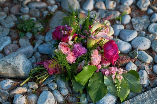 Wedding flowers, bridal bouquet closeup with roses and lilies on a Pebble and Rock Background