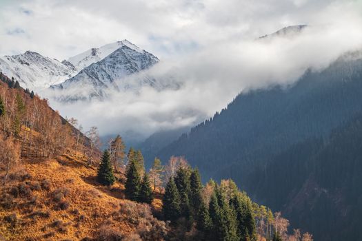 Very low clouds touch the peaks of the Almaty autumn mountains