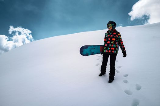 Active people enjoying the snow. Sports life and leisure. Snowboarder tourist girl walking on the mountain top. Ski park resort. Winter holidays and seasonal vacation travel.