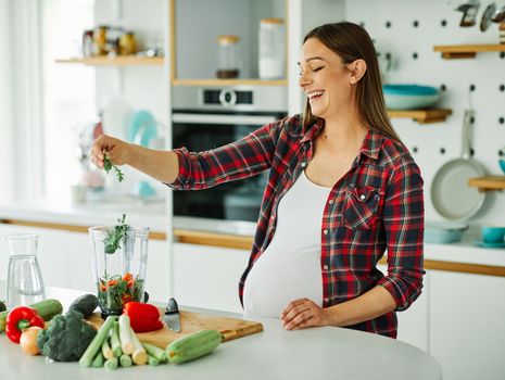 Portrait of a ytoung pregnant woman preparing a healthy meal in the kitchen