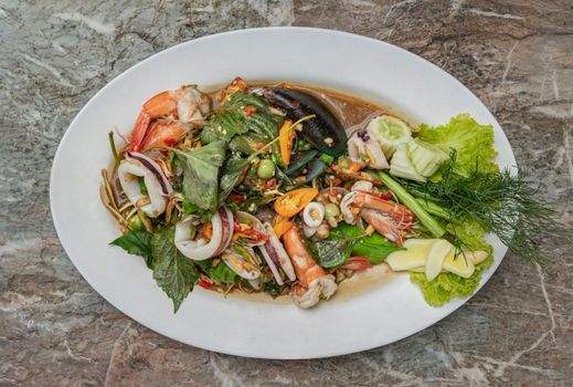 Stir-Fried Spicy seafood with herbs and spices served on white plate. Authentic thai food. 