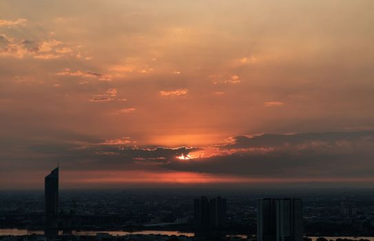Gorgeous panorama scenic of the sunrise or sunset with cloud on the orange sky over large metropolitan city in Bangkok.