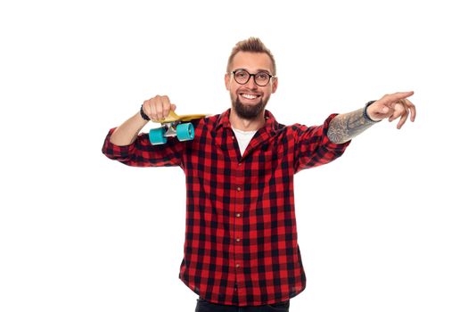 Hipster man over white background holding yellow skateboard. Active guy in plaid shirt with copy space
