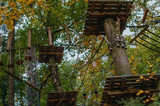 High ropes experience adventure tree park. Rope road course in trees. Climbing adventure rope park. Wood bridge and high wire activity.