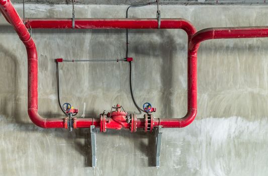 Red water or gas pipeline with gate pressure valve on concrete wall. Industrial tubes and valves, Line pipe industrial and extinguisher pump.