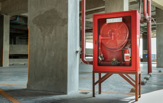 A red fire fighting equipment cabinet or fire extinguishing cabinet of fire protection set is located in condominium car parking. 