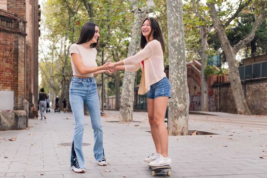 woman teaching her friend to ride a skateboard