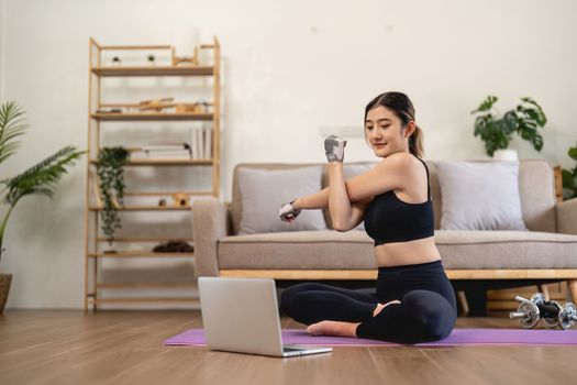 sport, fitness and healthy lifestyle concept - happy smiling young asian woman with laptop computer stretching arm at home