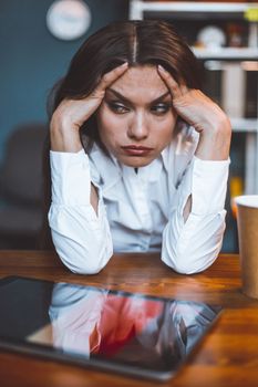 Exhausted business woman sits at workplace taking head in hands. Tired or bored female employee feels stress. Disappointment concept. Tinted image