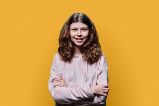 Portrait of smiling child schoolgirl on yellow studio background
