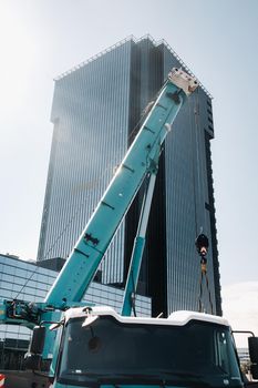 blue crane lifting mechanism with hooks near the glass modern building, crane and hydraulic high lift up to 120 meters