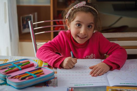 Smiling 6 year old girl does her homework