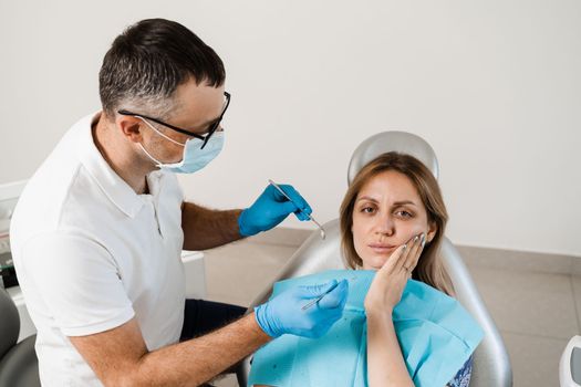 Dentist examines woman with toothache at consultation and treatment at the dentist in dentistry. Dentist treats caries teeth for girl.