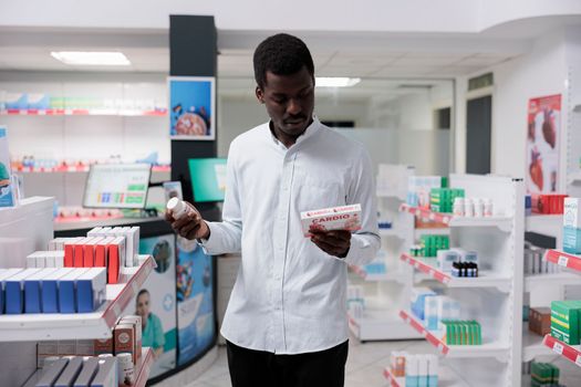 Young african american man choosing heart medication in drugstore