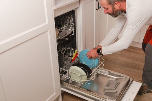 man putting dishes in the dishwasher