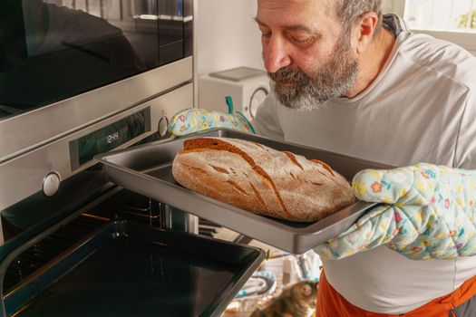 man putting bread in the oven