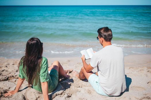 Young couple reading books on tropical beach
