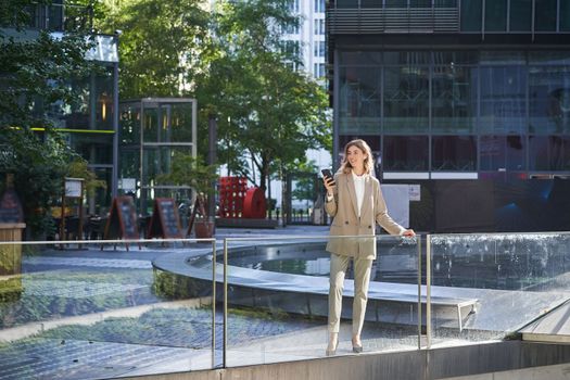 Confident businesswoman in beige suit, standing in power pose in city center