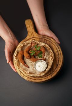 Top view of fried shrimp in breadcrumbs and sauce isolated on a black background. Grilled shrimp on a board in the hands of a waiter. Web banner text design.