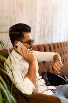 Arabic successful businessman or worker in white shirt with beard calling with his phone near his ear. Business and technology concept.