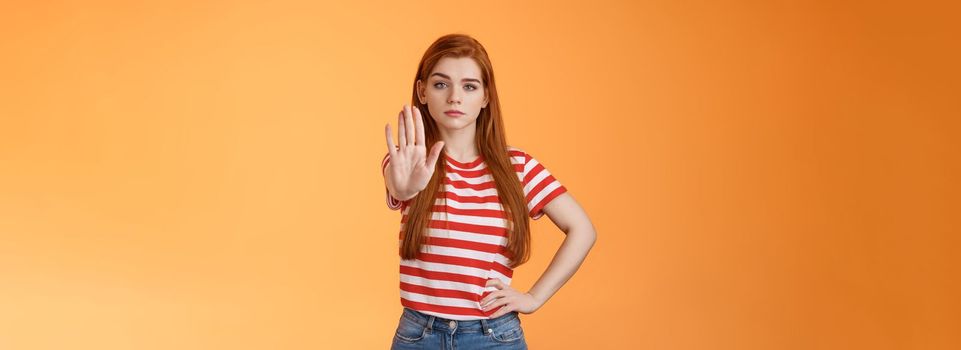 Serious-looking confident brave redhead girl oppose haters, fighting for freedom, prohibit illegal actions, extend hand stop enough, never or forbidden gesture, look determined camera