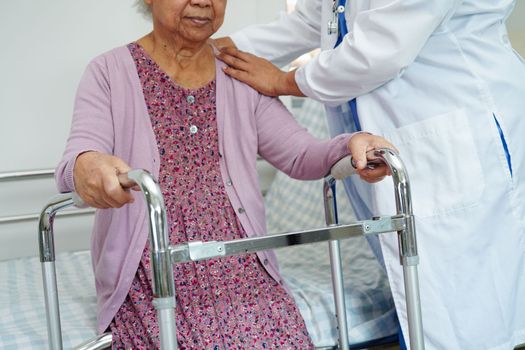 Doctor help Asian elderly woman disability patient walk with walker in nursing hospital, medical concept.
