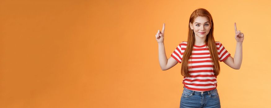Cute lovely redhead girlfriend hint boyfriend what buy anniversary, pointing copy space promo, indicate fingers up, look camera assured, determined get what want, stand orange background