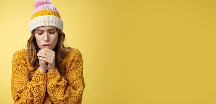 Close-up upset uncomfortable cute tender young caucasian woman breathing warm air hands warm-up freezing-cold outside stooping trembling wearing light clothes, standing yellow background