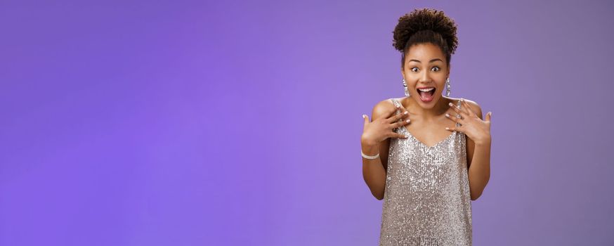 Amazed surprised attractive african-american young woman in glittering evening night dress scream happiness pointing herself amused cannot believe lucky win casino lottery, blue background