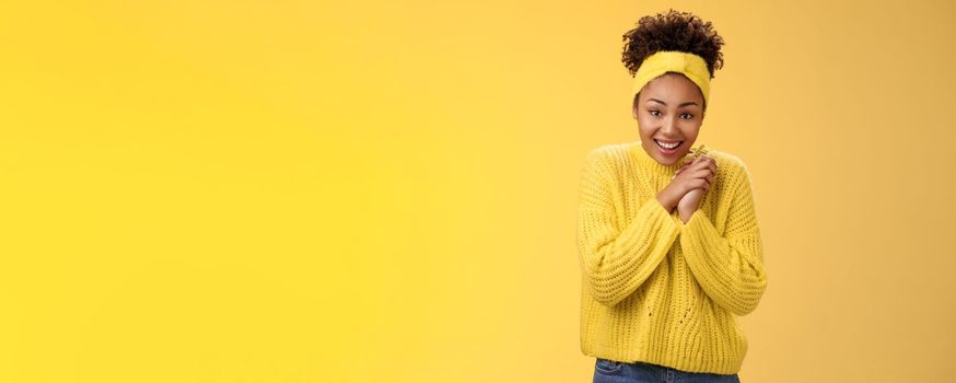 Touched tender african-american woman press palms together sighing happily smiling enjoying lovely scene grinning look passionate delighted grateful have united supportive family, yellow background