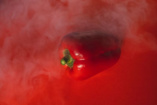 SWEET, fresh RED PEPPER ON A RED BACKGROUND WITH A LIGHT SMOKE