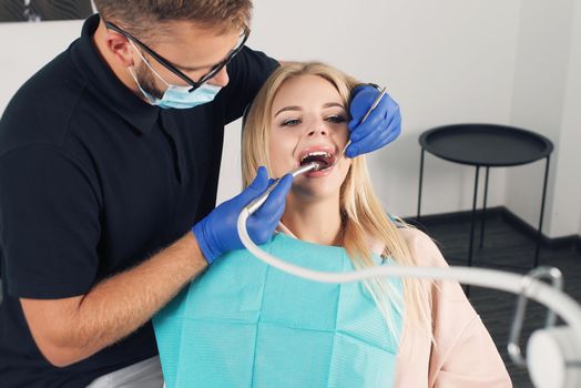 Portrait of a dentist who treats teeth of young woman patient.