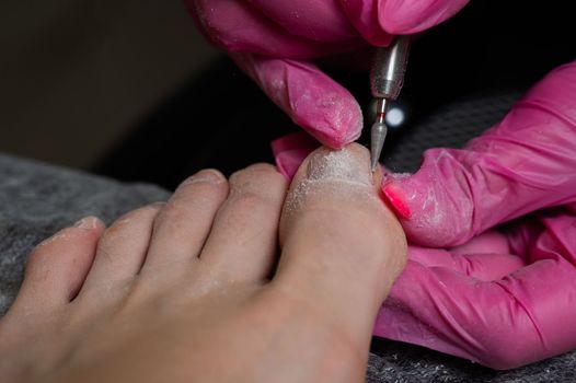 The master makes hardware pedicures to the client. Cuticle treatment.