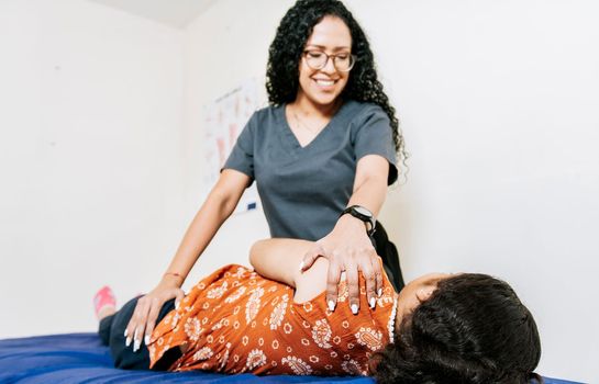 Woman doing shoulder rehabilitation physiotherapy. Physiotherapist rehabilitating shoulder to patient lying on her side. Shoulder and back treatment and rehabilitation concept