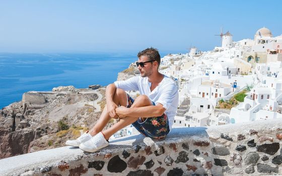 Young men at Oia Santorini Greece on a sunny day during summer with whitewashed homes and churches