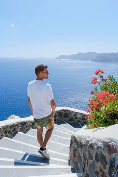 Young men tourist visit Oia Santorini Greece during summer with whitewashed homes and churches
