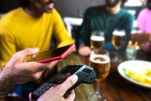 Close up of man hand paying bill with mobile phone at a bar. Selective focus on foreground. Copy space.